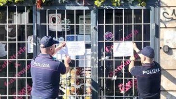 Agenti della Polizia affiggono i sigilli di chiusura su un locale a Roma.