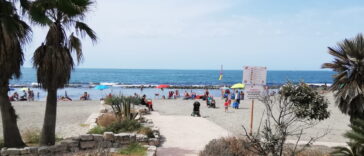 Spiaggia di Ostia con persone, ombrelloni colorati e mare sullo sfondo