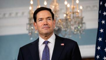 Marco Rubio durante un evento ufficiale con bandiera americana sullo sfondo