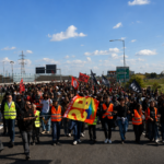 Corteo di manifestanti e lavoratori durante uno sciopero con bandiere e giubbotti catarifrangenti