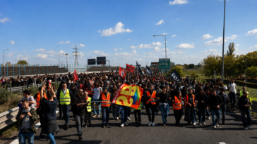 Corteo di manifestanti e lavoratori durante uno sciopero con bandiere e giubbotti catarifrangenti