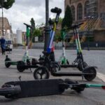 Monopattini elettrici parcheggiati e uno caduto a terra in una strada del centro di Roma vicino ai Fori Imperiali.