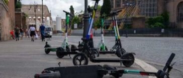 Monopattini elettrici parcheggiati e uno caduto a terra in una strada del centro di Roma vicino ai Fori Imperiali.