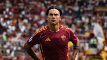 Paulo Dybala con la maglia della Roma durante una partita allo Stadio Olimpico, concentrato in campo davanti ai tifosi giallorossi.