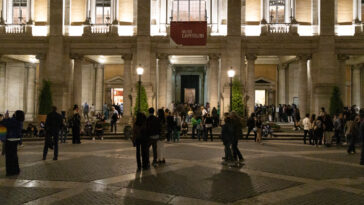 Persone in fila davanti ai Musei Capitolini illuminati durante la Notte dei Musei a Roma, con visitatori che affollano Piazza del Campidoglio nelle ore serali.