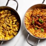 Due piatti di pasta serviti in tegamini d’acciaio: una carbonara con rigatoni e una pasta al sugo con polpette, simbolo delle nuove aperture gastronomiche a Roma.