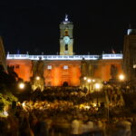 Piazza del Campidoglio illuminata durante un evento serale a Roma, con centinaia di persone riunite sulla scalinata e nella piazza davanti al Palazzo Senatorio.