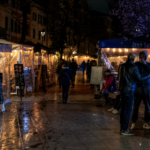 Via del Pigneto nelle ore serali, con persone che passeggiano tra locali, dehors illuminati e tavolini all'aperto nel cuore della movida romana.