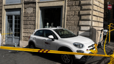 Il taxi coinvolto nell'incidente fermo sul marciapiede davanti a un negozio di via del Tritone, transennato dalla polizia locale dopo aver terminato la sua corsa contro la vetrina.