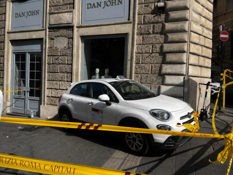 Il taxi coinvolto nell'incidente fermo sul marciapiede davanti a un negozio di via del Tritone, transennato dalla polizia locale dopo aver terminato la sua corsa contro la vetrina.