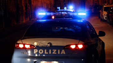 Auto della Polizia di Stato con i lampeggianti accesi durante un intervento notturno in una strada di Roma.
