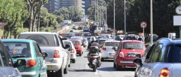 Traffico intenso su una strada di Roma, con auto e scooter in coda vicino a un'area interessata da lavori e modifiche alla viabilità.