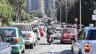 Traffico intenso su una strada di Roma, con auto e scooter in coda vicino a un'area interessata da lavori e modifiche alla viabilità.