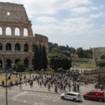 Vista del Colosseo a Roma con numerosi turisti e visitatori nell’area circostante durante una giornata estiva.
