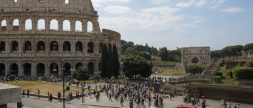 Vista del Colosseo a Roma con numerosi turisti e visitatori nell’area circostante durante una giornata estiva.