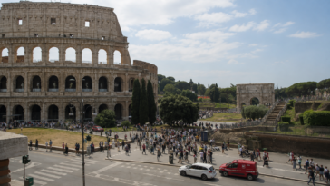 Vista del Colosseo a Roma con numerosi turisti e visitatori nell’area circostante durante una giornata estiva.