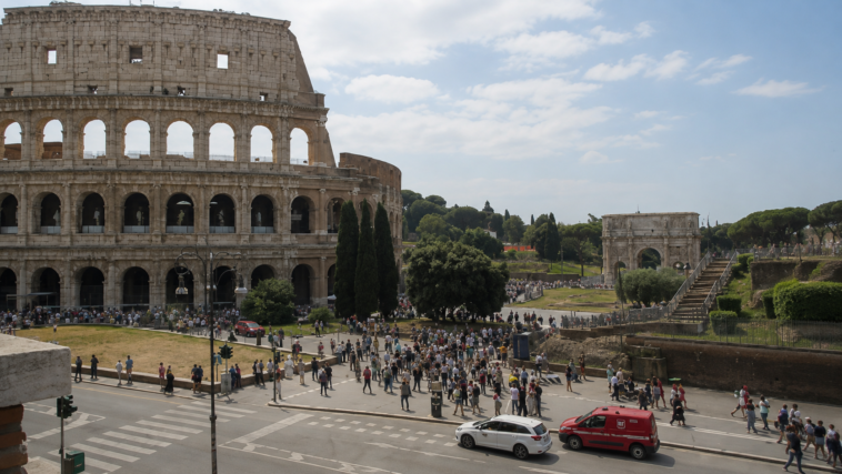 Vista del Colosseo a Roma con numerosi turisti e visitatori nell’area circostante durante una giornata estiva.