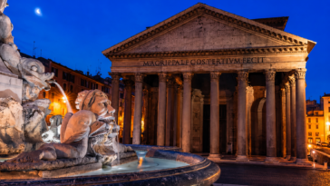 Vista serale del Pantheon di Roma illuminato, con la Fontana del Pantheon in primo piano e il cielo blu intenso sullo sfondo.