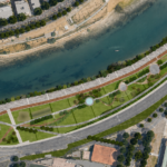 Rendering dall’alto del progetto del nuovo parco Tevere Roma Sud, con aree verdi, percorsi ciclopedonali e piazze lungo la sponda del fiume a Roma.