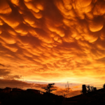 Cielo di Roma illuminato da intense tonalità arancioni e gialle, con particolari formazioni nuvolose sopra i tetti della città.
