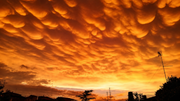 Cielo di Roma illuminato da intense tonalità arancioni e gialle, con particolari formazioni nuvolose sopra i tetti della città.