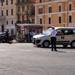 Agente della Polizia Locale dirige il traffico in una strada di Roma durante modifiche alla viabilità.