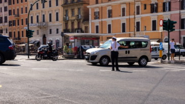 Agente della Polizia Locale dirige il traffico in una strada di Roma durante modifiche alla viabilità.