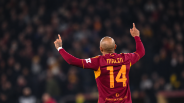 Calciatore della Roma con la maglia numero 14 visto di spalle durante una partita, con le braccia alzate.