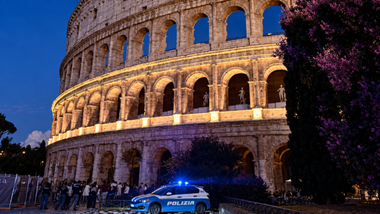Colosseo illuminato di notte a Roma con una pattuglia della Polizia davanti all’Anfiteatro Flavio.