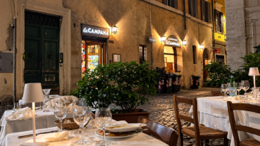 Tavoli apparecchiati all’aperto davanti al ristorante La Campana, in una strada del centro storico di Roma.