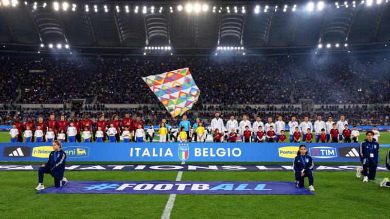 Nazionali di Italia e Belgio schierate sul campo dello Stadio Olimpico prima di una partita, con gli spalti pieni di tifosi.