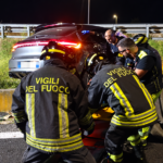 Vigili del Fuoco durante le operazioni di soccorso accanto a un’auto finita fuori strada contro il guardrail nella notte.