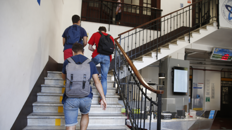 Studenti con zaini salgono le scale all’interno di un istituto scolastico.