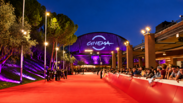 Red carpet della Festa del Cinema di Roma all'Auditorium Parco della Musica, con pubblico lungo le transenne, illuminazione viola e ingresso della manifestazione sullo sfondo.