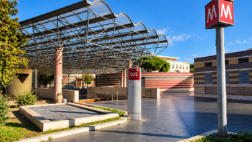 Ingresso della stazione Cipro della Metro A di Roma, con pensilina in vetro e metallo, insegna rossa della metropolitana e colonnina SOS.