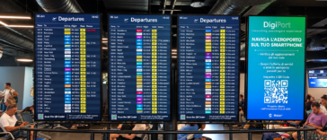 Tabelloni digitali delle partenze all’aeroporto di Roma Fiumicino, con orari, destinazioni e stato dei voli, mentre i passeggeri attendono nell’area imbarchi.