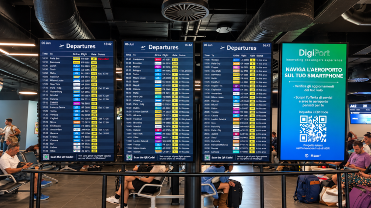 Tabelloni digitali delle partenze all’aeroporto di Roma Fiumicino, con orari, destinazioni e stato dei voli, mentre i passeggeri attendono nell’area imbarchi.